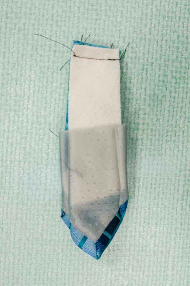 insert lobster clasp into cut end of tie. sew cut end of tie closed.