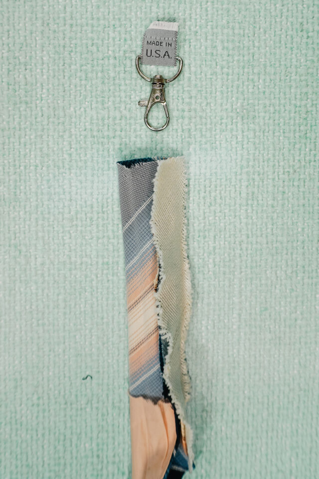 cut a piece from the skinny end of the tie. turn right side out. wrap tag around lobster clasp.