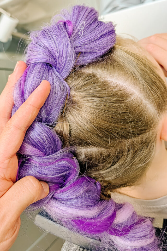 use bobby pins to pull purple braid down around hair braid